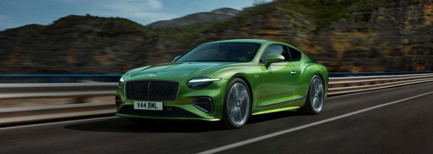 A 2026 Bentley Continental driving fast on a country road.