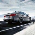 Silver 2020 BMW M5 driving on a road with mountains in the background