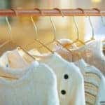 Closeup on modern copper clothes rack with sweaters on hangers.