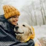 Photo of smiling woman and her dog in a snowy day