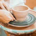 Woman working on a pottery wheel to make a mug