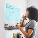 Shot of a young woman marking something on a poster on her wall at home