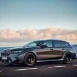 A sleek BMW M5 Touring Wagon parked, showcasing its sporty design and powerful stance in a modern urban setting.
