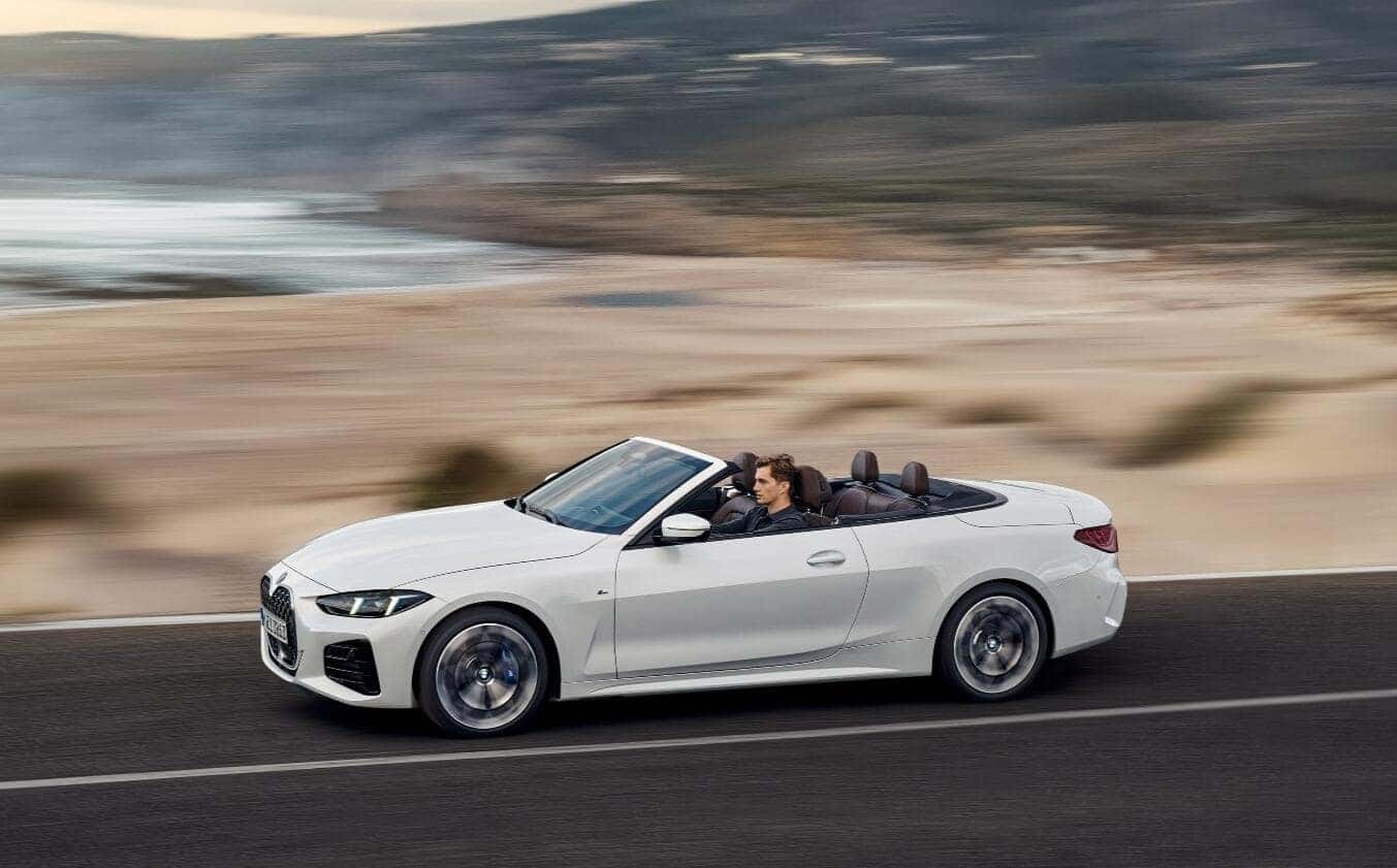 A sleek 2025 BMW 4-series convertible parked, showcasing its elegant design and open-top feature under a clear blue sky.
