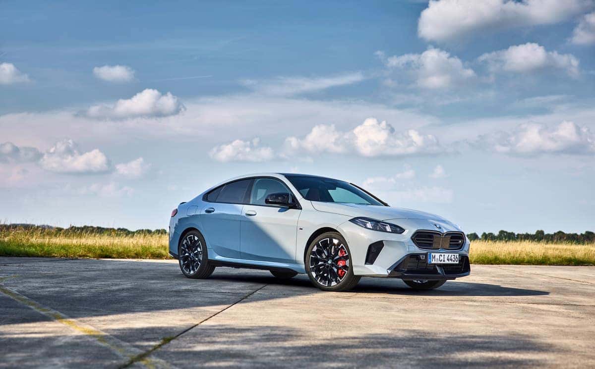 A sleek BMW 2 Series Gran Coupe parked under a blue sky, showcasing its sporty design and elegant lines.