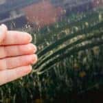 Person hand showing yellow pollen grains pulled from car. Trees and flowers pollen covering car exterior in spring, witch can damage your car's paint concept.