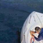 A sailor washes his speedboat early in the morning before going to sea.