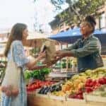 woman buying produce from a vendor at a farmers' market