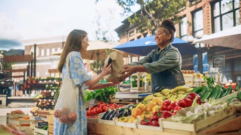 woman buying produce from a vendor at a farmers' market