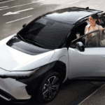 Toyota-Subaru EV Collaboration -- white bZ4X parked on the side of the street with a woman stepping into the car