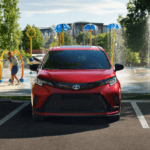 Sienna Family Vacation Choice: Parked red Toyota Sienna outside of a waterpark with a family playing in the water.
