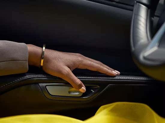 A close-up of a woman's hand resting on the Lexus RX interior door panel with a yellow dress visible.