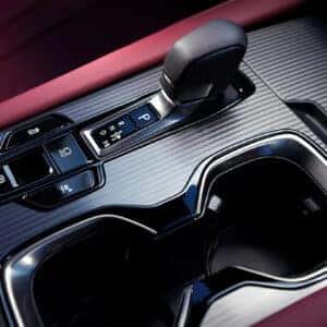 Close-up of the Lexus RX center console with a gear shift and drive mode buttons, featuring a red leather interior.