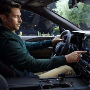 A man in a green jacket sitting in the driver’s seat of the Lexus RX, using the touchscreen navigation system.