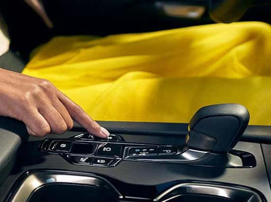 A woman's hand pressing the drive mode button on the Lexus RX center console.