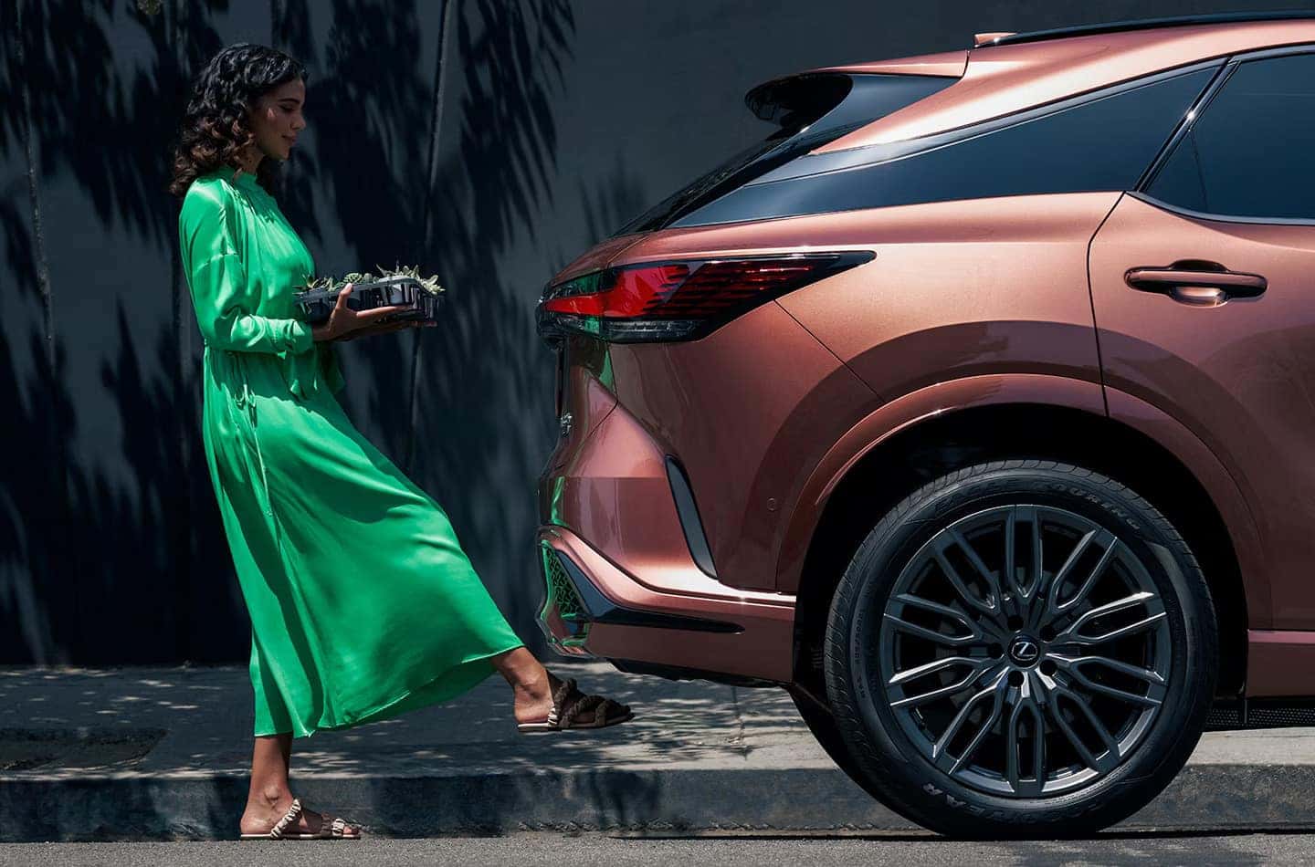 Woman in a green dress using the hands-free power liftgate feature on the 2025 Lexus RX with a kick sensor.