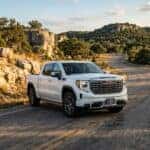 2026 GMC Sierra 1500 pickup truck in Glacier White Tricoat driving along a road in austin tx hill country