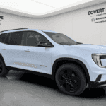 2026 GMC Acadia Denali parked in front of Covert Buick GMC Bee Cave showroom in Austin, Texas with Hill Country views in the background
