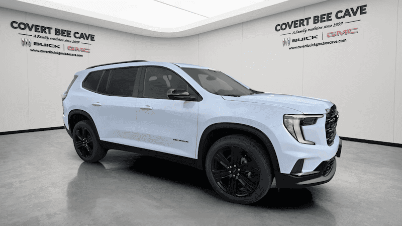 2026 GMC Acadia Denali parked in front of Covert Buick GMC Bee Cave showroom in Austin, Texas with Hill Country views in the background