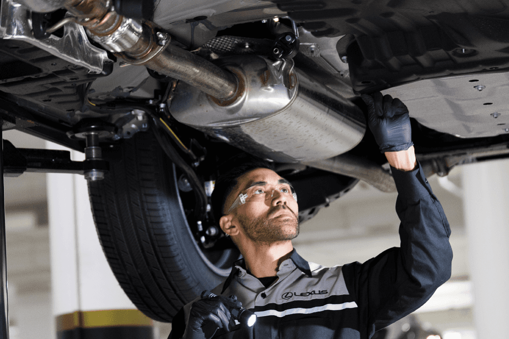 Service technician working on the underside of a Lexus vehicle