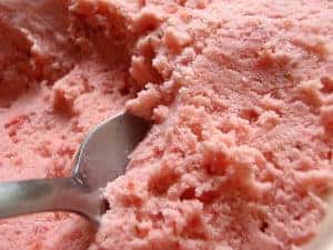 Spoon scooping up fresh strawberry ice cream.