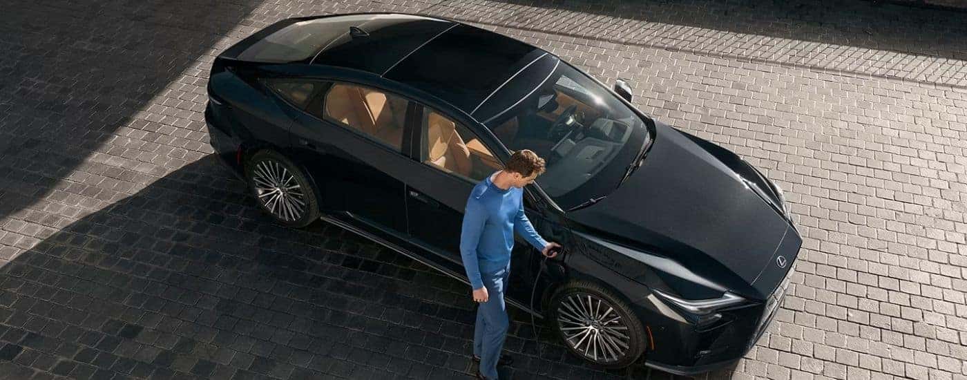 A man plugging in a black 2026 Lexus ES 350e Luxury.