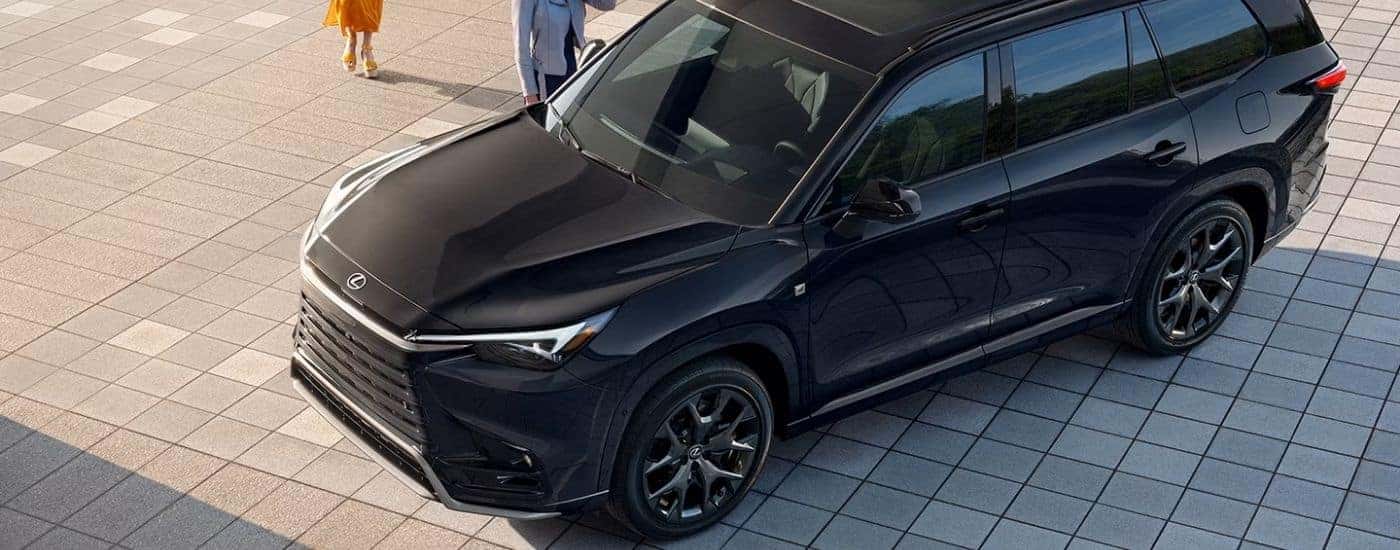 A black 2026 Lexus TX 500h F Sport parked on a driveway angled left.