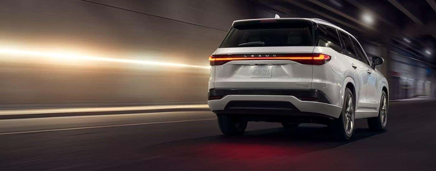 Rear view of a white 2026 Lexus TX 350 Luxury AWD driving in a tunnel.