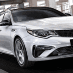 2020 kia optima white exterior driving down city road close up