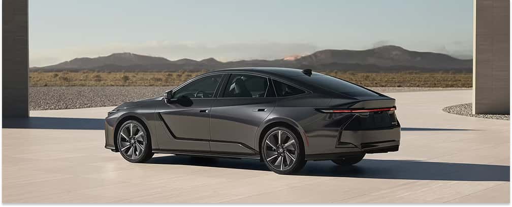 Rear profile of a dark gray 2026 Lexus ES sedan with mountains in the background.