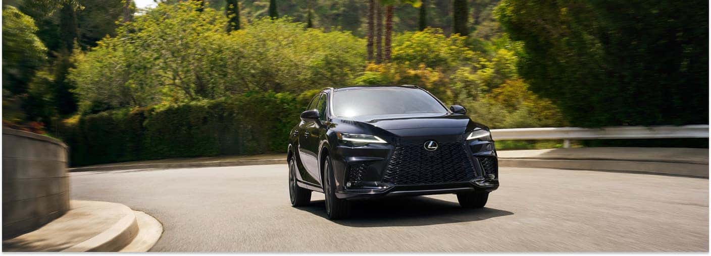 Front three-quarter view of a black 2026 Lexus RX driving on a curved road.