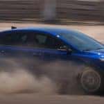 blue kia forte driving through dry dirt