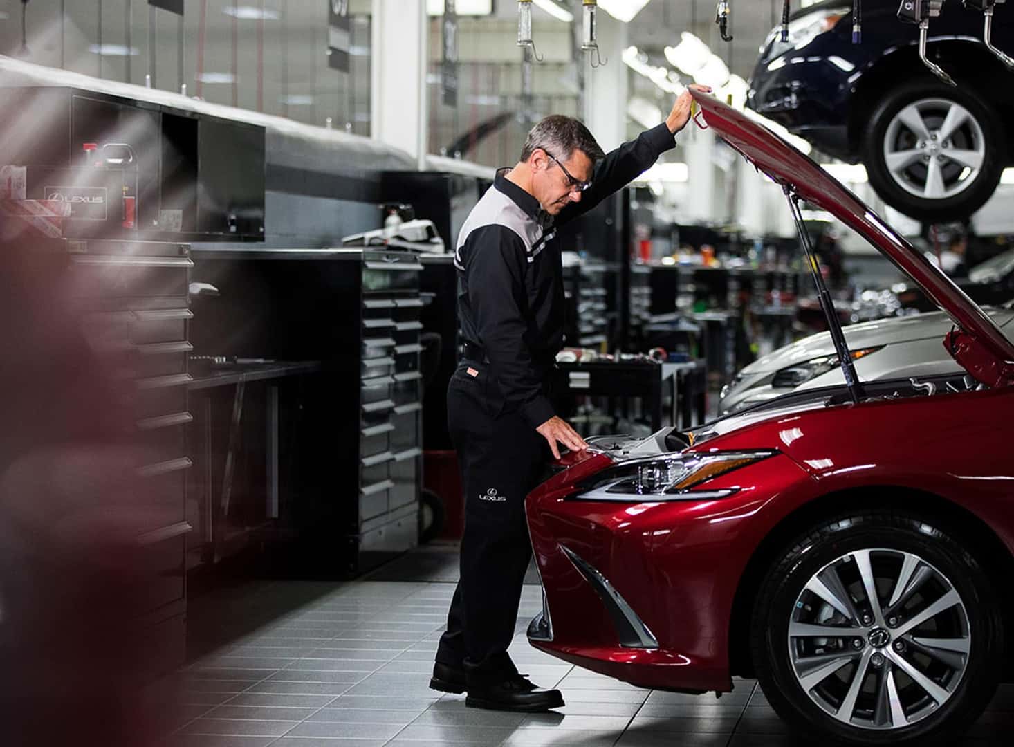 Lexus service tech looking under the hood of a car