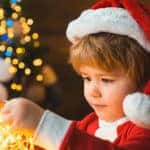 small autism child holding bright gold garland of tiny holiday lights