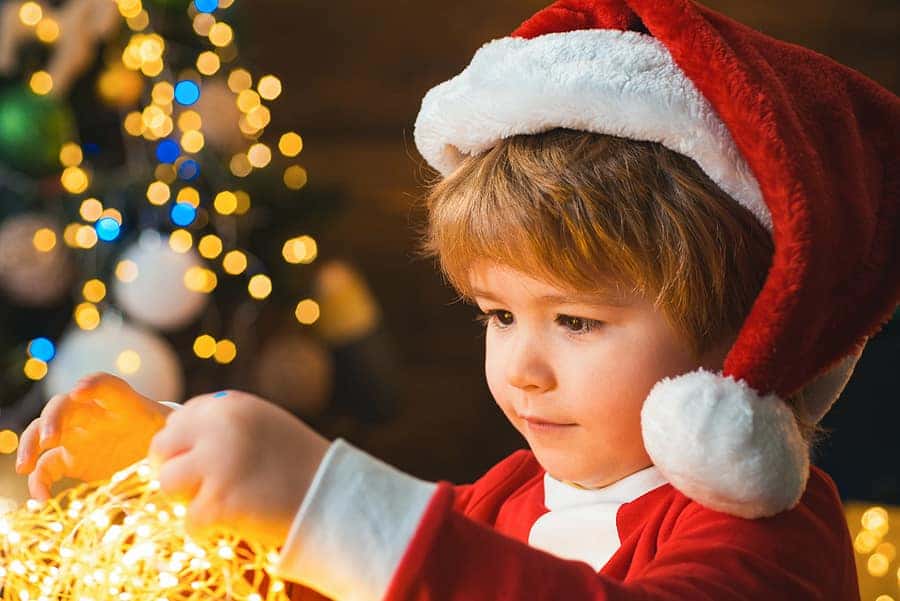 autistic child holding bright gold garland of tiny holiday lights