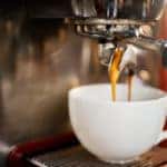 Closeup shot of an espresso maker pouring coffee into a cup inside of a café