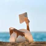 Young woman reads a book on the beach