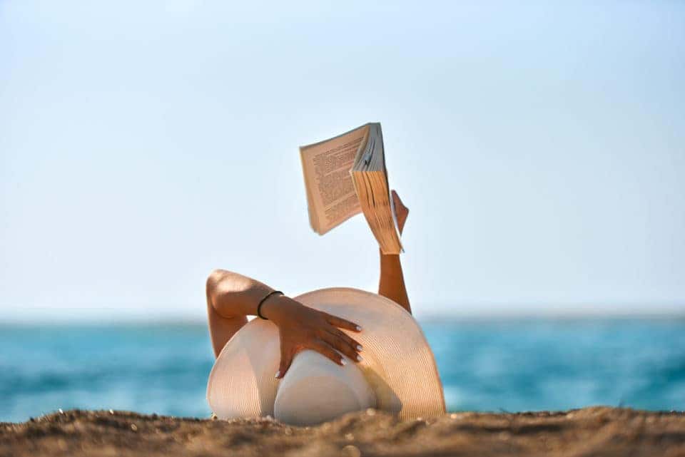 Young woman reads a book on the beach