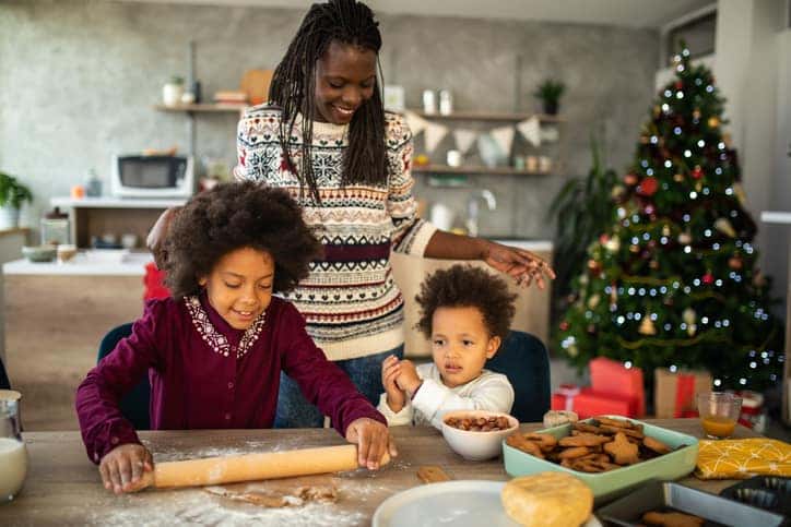 Sisters helping their mom to make good Christmas cookies in their kitchen