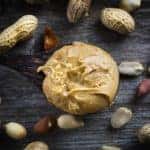 Spoon of peanut butter on wooden background