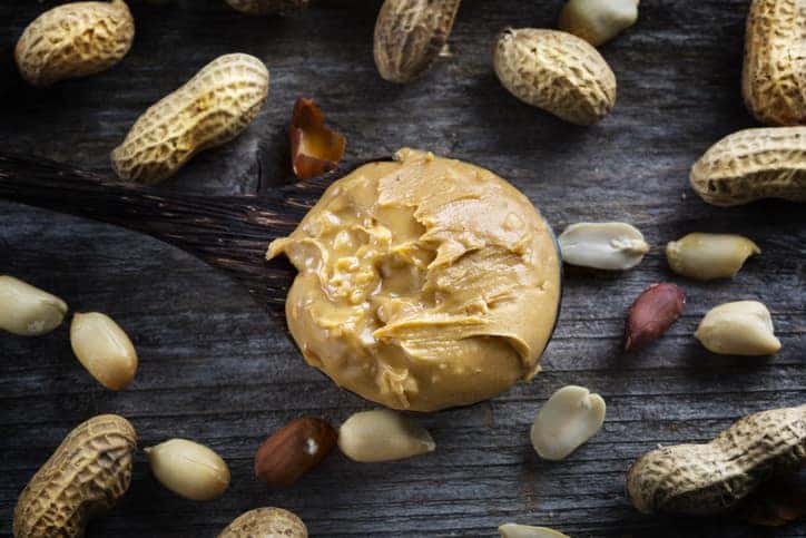 Spoon of peanut butter on wooden background