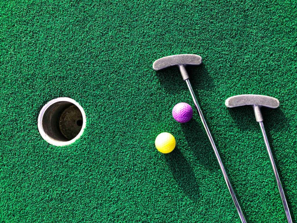 golf clubs and balls on putting green