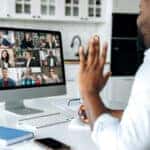Video call, online conference. Over shoulder view of african american man at computer screen with multinational group of successful business people, virtual business meeting, work from home concept