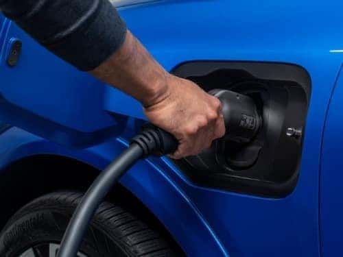 2025 Chevrolet Equinox EV close up view of man charging vehicle