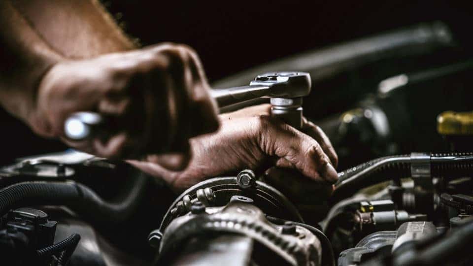 Auto mechanic working on car engine in mechanics garage. 