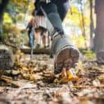 Hiker woman with trekking sticks climbs steep on mountain trail
