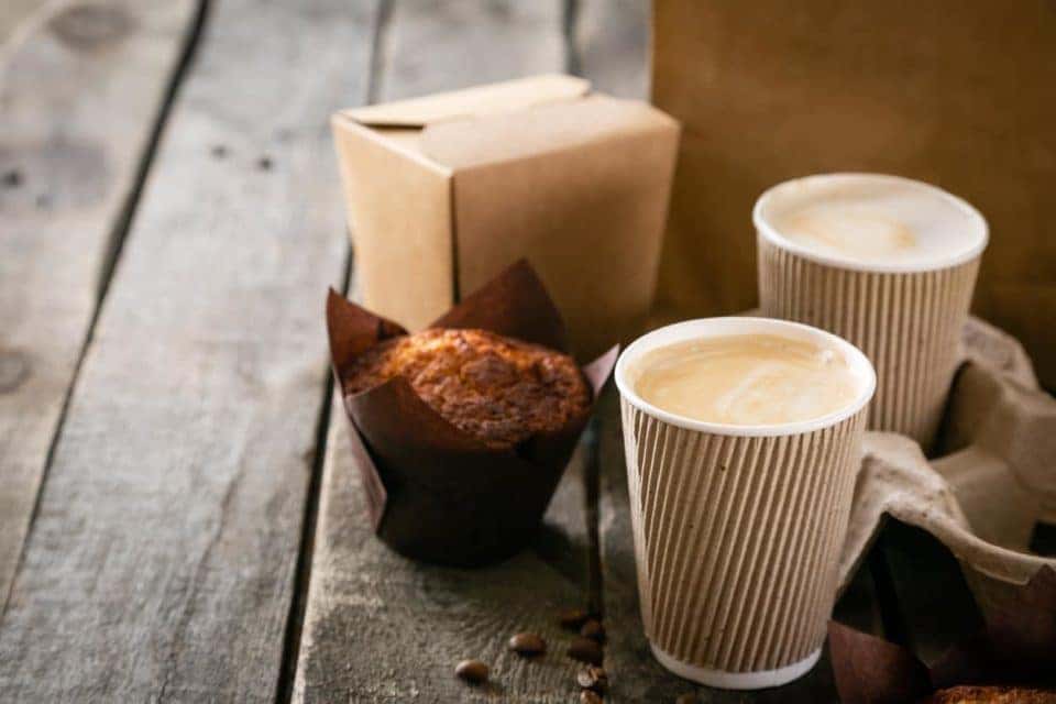 Coffee to go with muffin on wood background