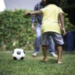Father and son playing soccer in backyard