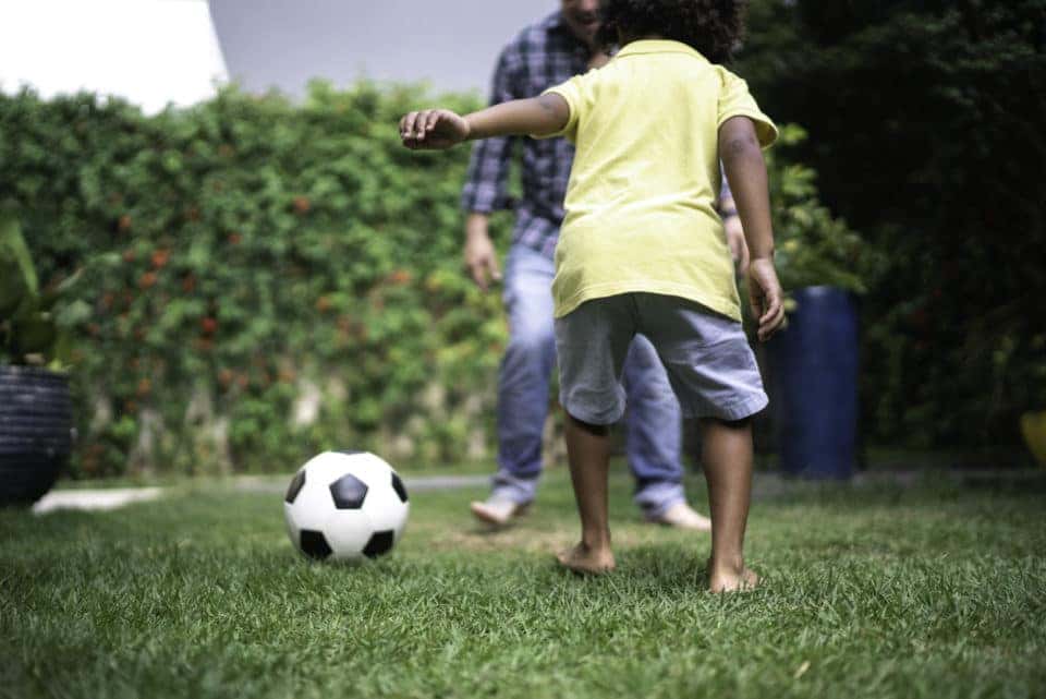 Father and son playing soccer in backyard