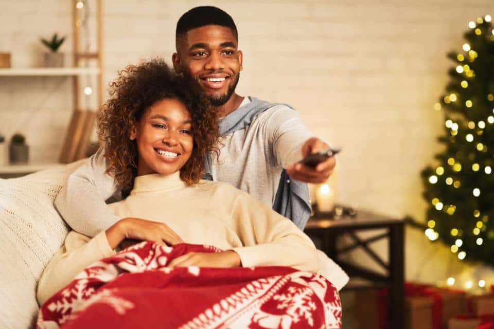 Couple watching movie with Christmas tree in the background